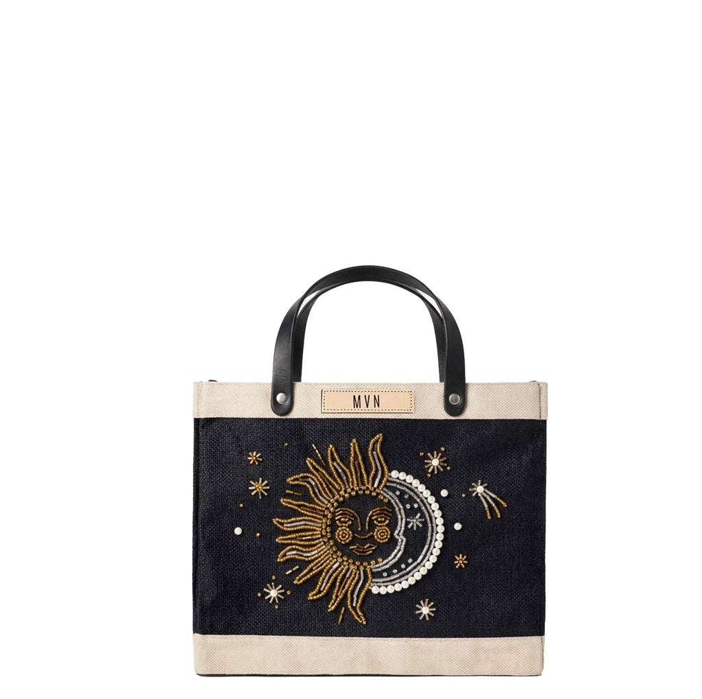 Petite Market Bag in Black with Sun & Moon Bead, front view: gold and pearl beaded sun and crescent moon embroidery with beaded stars on black jute, natural leather label personalized with initials, black leather handles