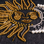 Close-up detail of the beaded sun and moon on the Petite Market Bag in Black: gold seed and bugle beads forming the sun's rays and face, silver beads and white pearls outlining the crescent moon on black jute