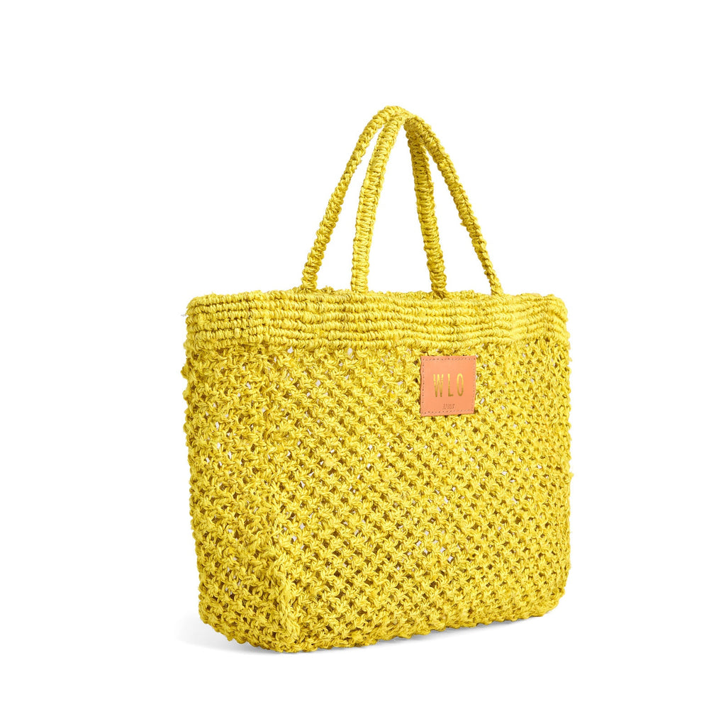 Petite Mercado Tote in Ocre — three-quarter view showing the open weave and crocheted handles, gold foil monogram on the leather patch
