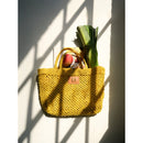 Petite Mercado Tote in Ocre — photographed against a sunlit wall, filled with leeks and fruit from a market run