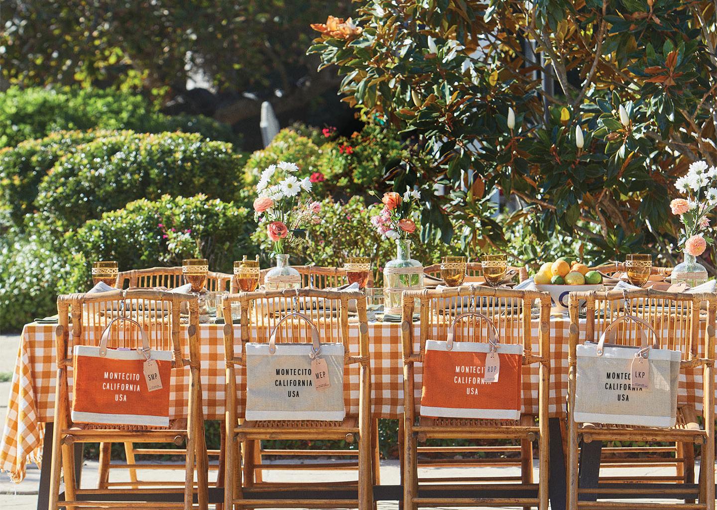Personalized Apolis bags on rattan chairs at a garden gathering
